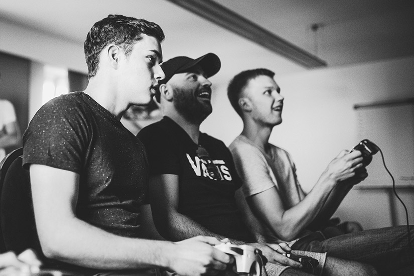 Black and white photo of Marius, Kevin and Alex playing some Mario Kart.